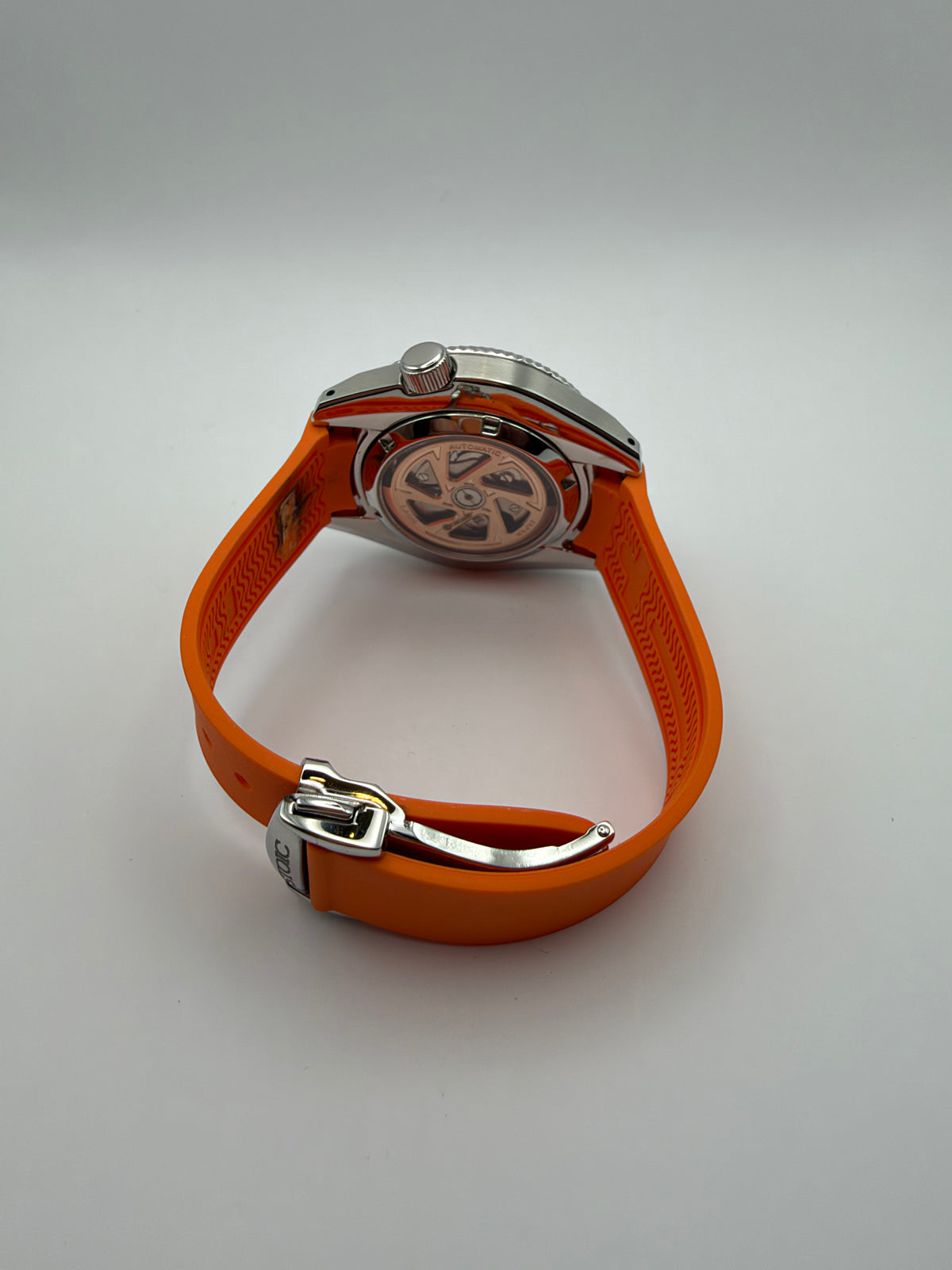 Equinox rear view showing a display caseback and orange strap with a silver-tone folding clasp.