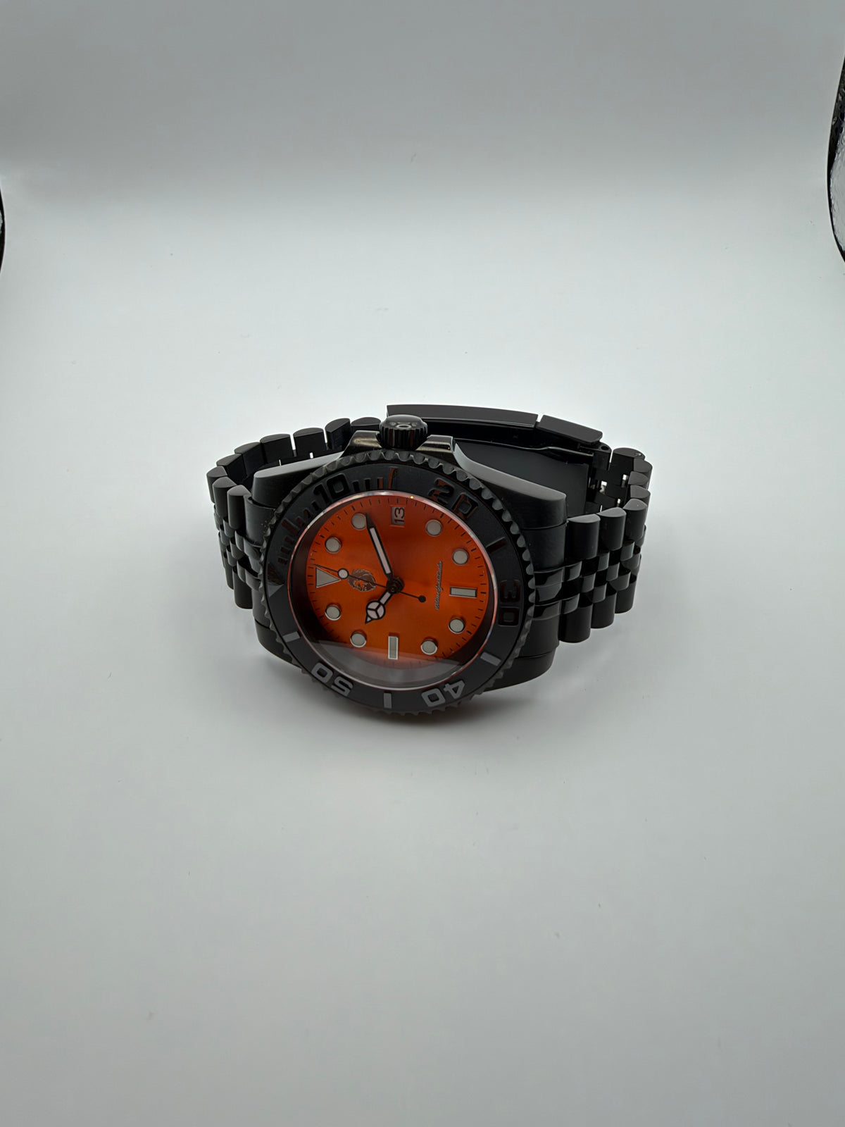 Ember Depth resting at an angle, showing the orange dial, black case and black bracelet.