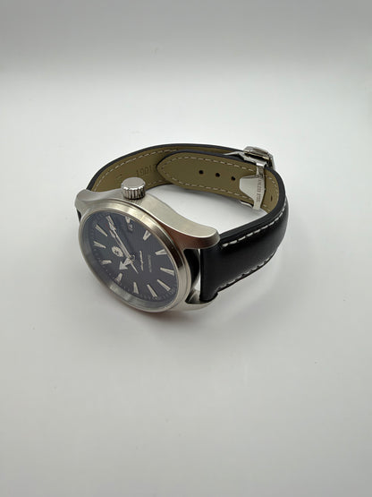Resolute resting at an angle, showing the black stitched strap and silver-tone case profile.