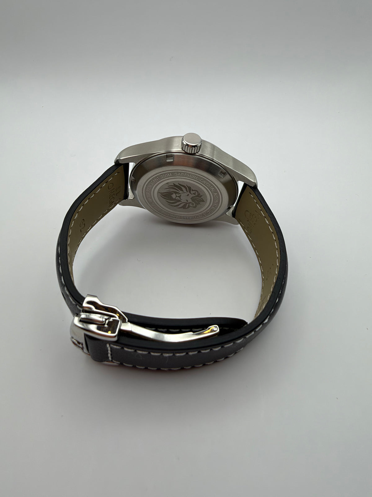 Resolute rear view with a lion-engraved caseback and a black stitched strap with folding clasp.