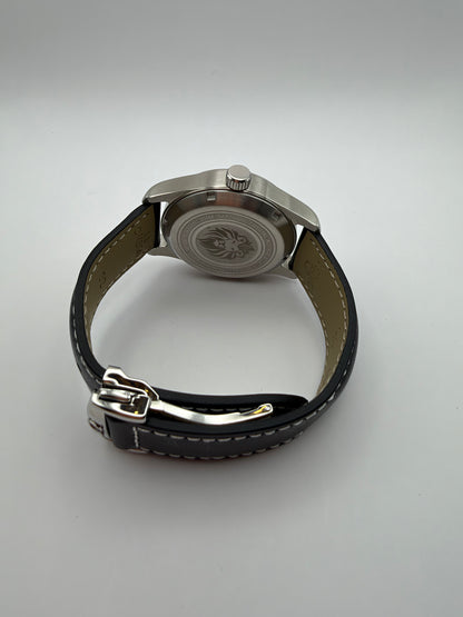 Resolute rear view with a lion-engraved caseback and a black stitched strap with folding clasp.
