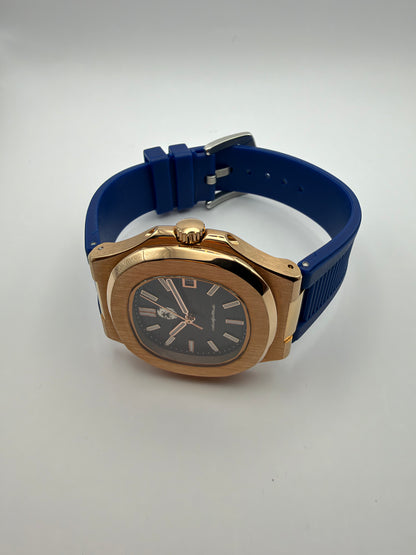 Nocturne resting on its side, showing the gold-tone case and blue strap.