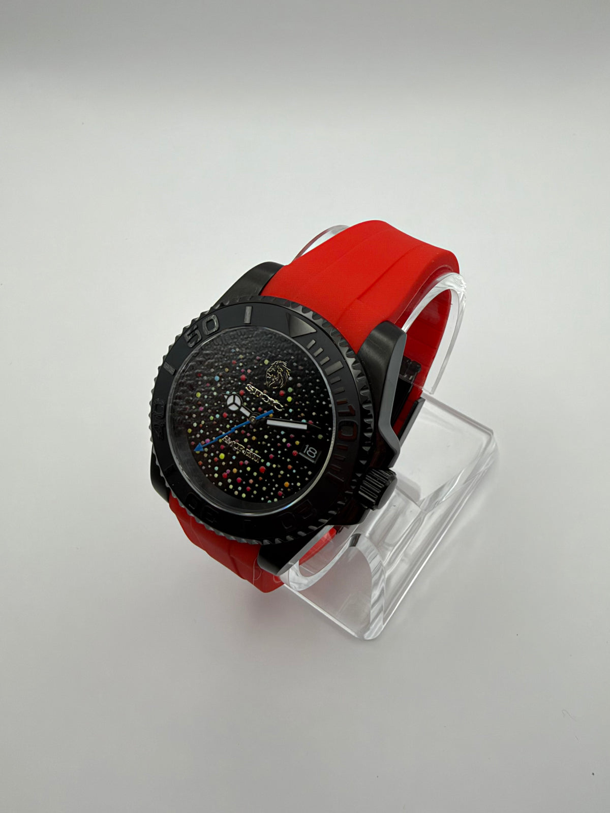 Memento Diver at an angle, with a black multicolor-dot dial, black bezel and red strap.
