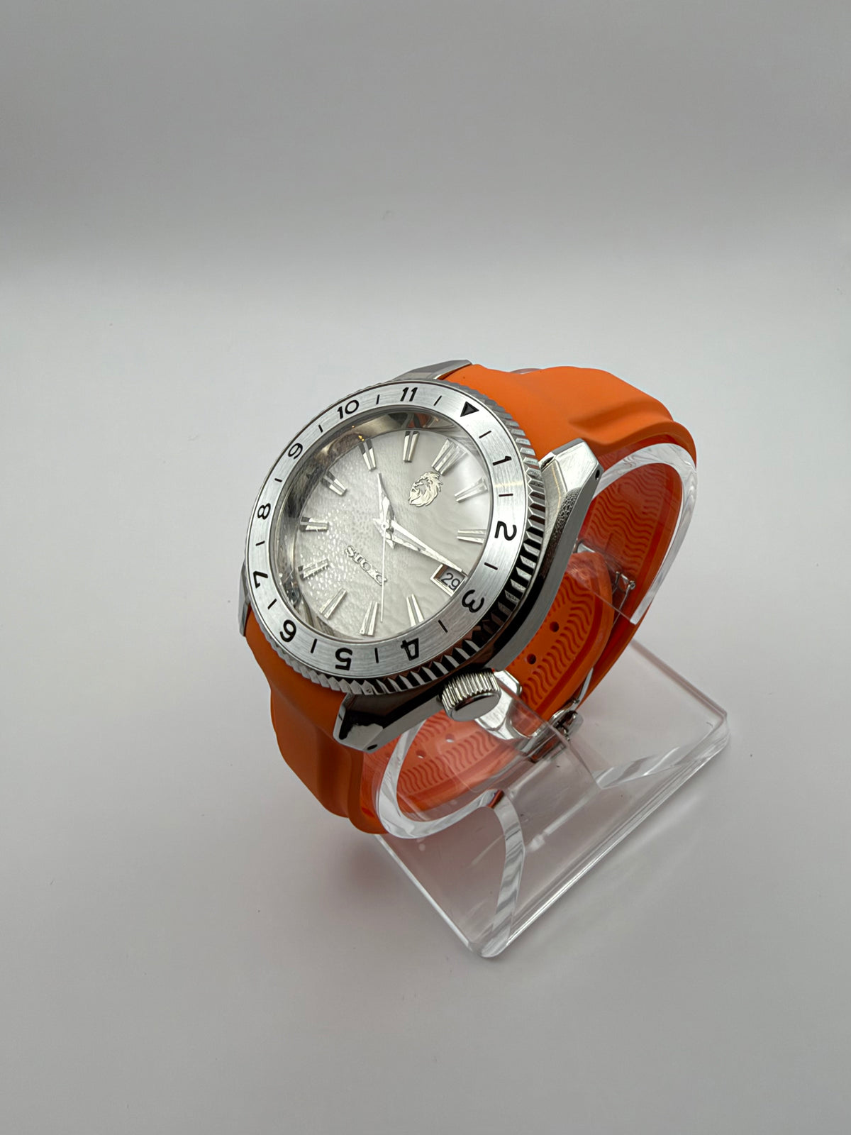 Equinox at an angle, showing its white dial, silver-tone case and orange strap.