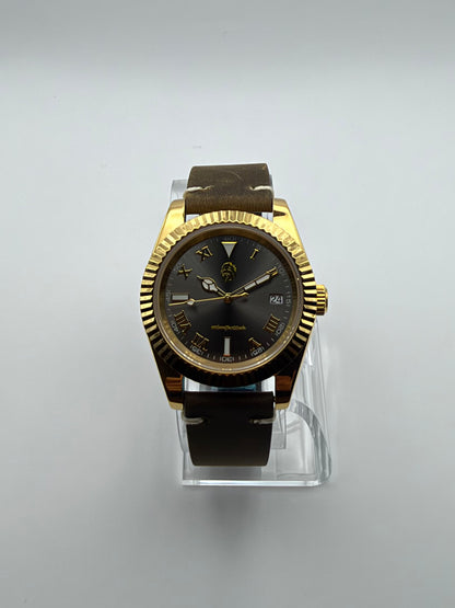 Auctor front view showing the dark dial, Roman numerals, date window and gold-tone case.