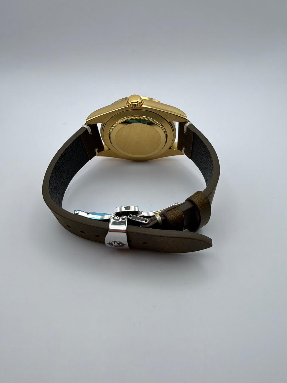 Auctor rear view showing a plain gold-tone caseback and brown strap with a folding clasp.