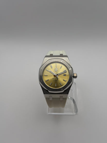 Thalassa Gold front view, with a gold-color dial, silver-tone octagonal bezel and cream-white strap.