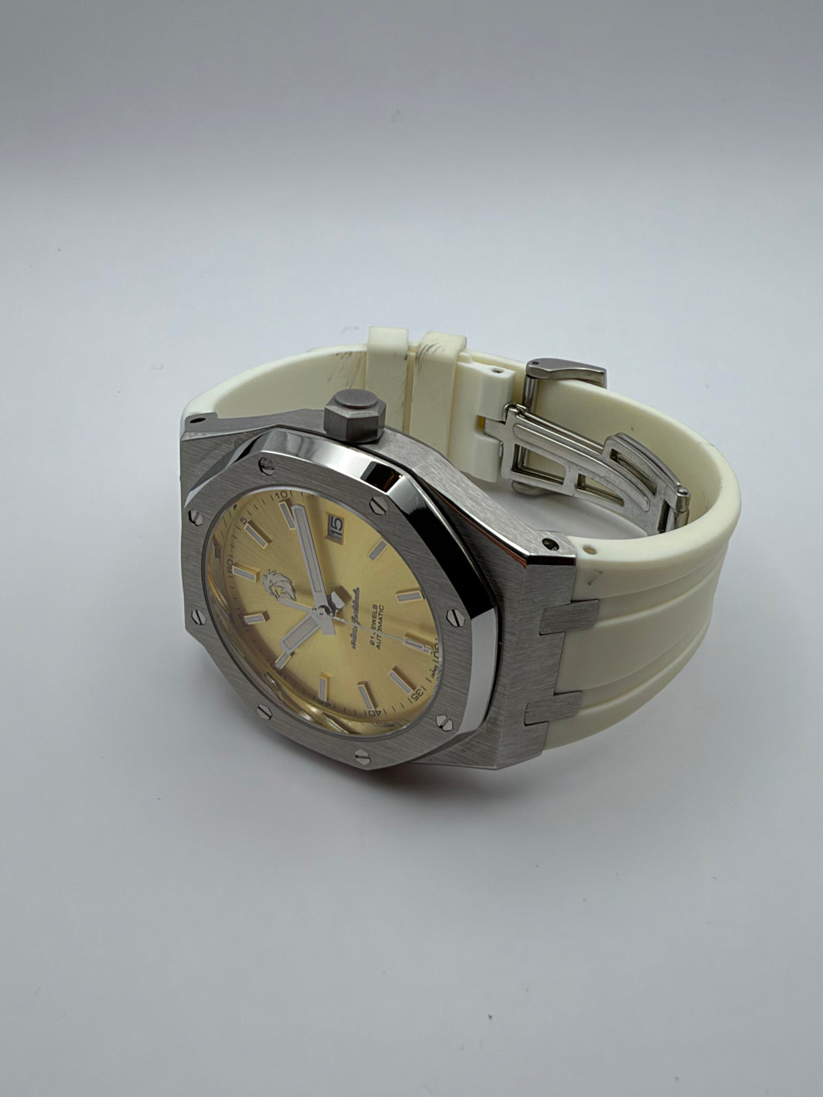 Thalassa Gold resting at an angle, showing its gold-color dial, octagonal case and cream-white strap.