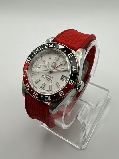 Valiant GMT at an angle, with a white dial, black and red bezel, and textured red strap.