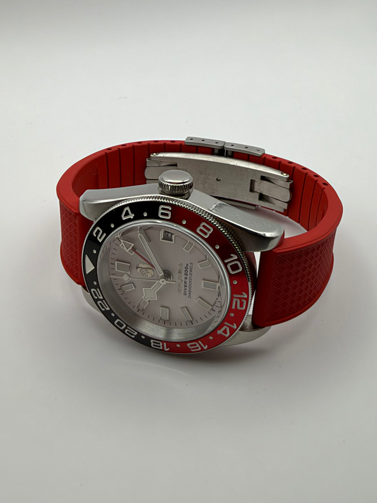 Valiant GMT resting at an angle, showing the red strap and silver-tone case profile.