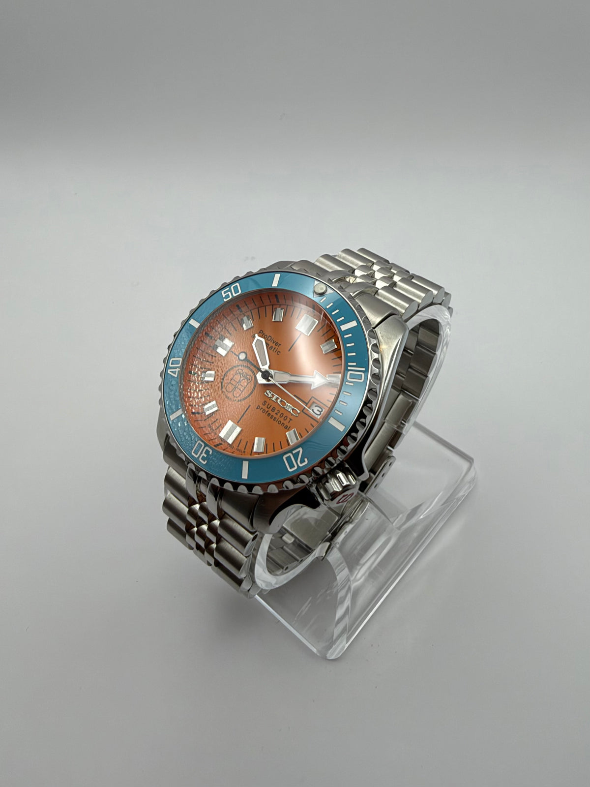 Thalassa Orange at an angle, showing its turquoise bezel and silver-tone bracelet.