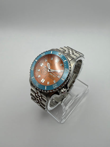 Thalassa Orange at an angle, showing its turquoise bezel and silver-tone bracelet.