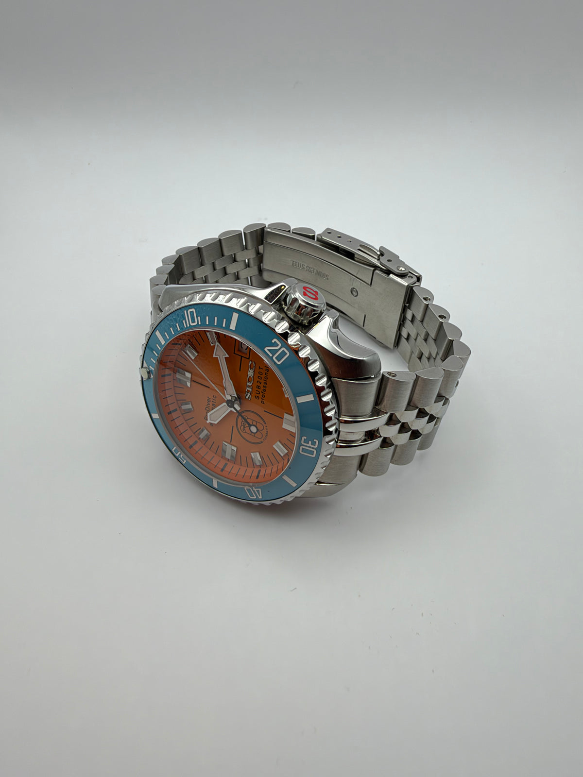 Thalassa Orange resting at an angle, showing the orange dial and multi-row metal bracelet.