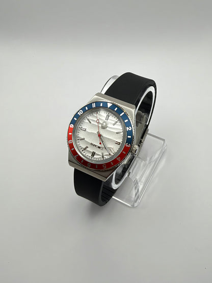 Voyager at an angle, with a white textured dial, red and blue bezel, and black strap.