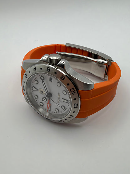 Navigator resting at an angle, showing the orange strap, crown and folding clasp.