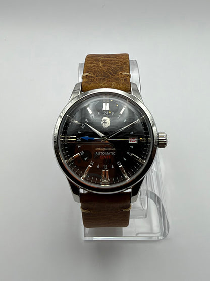 Ethos GMT front view, with a dark dial, blue arrow hand and brown strap with light stitching.