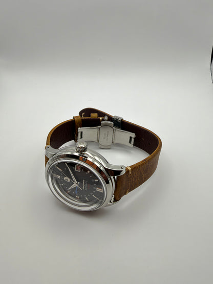 Ethos GMT resting at an angle, showing its silver-tone case, brown strap and folding clasp.