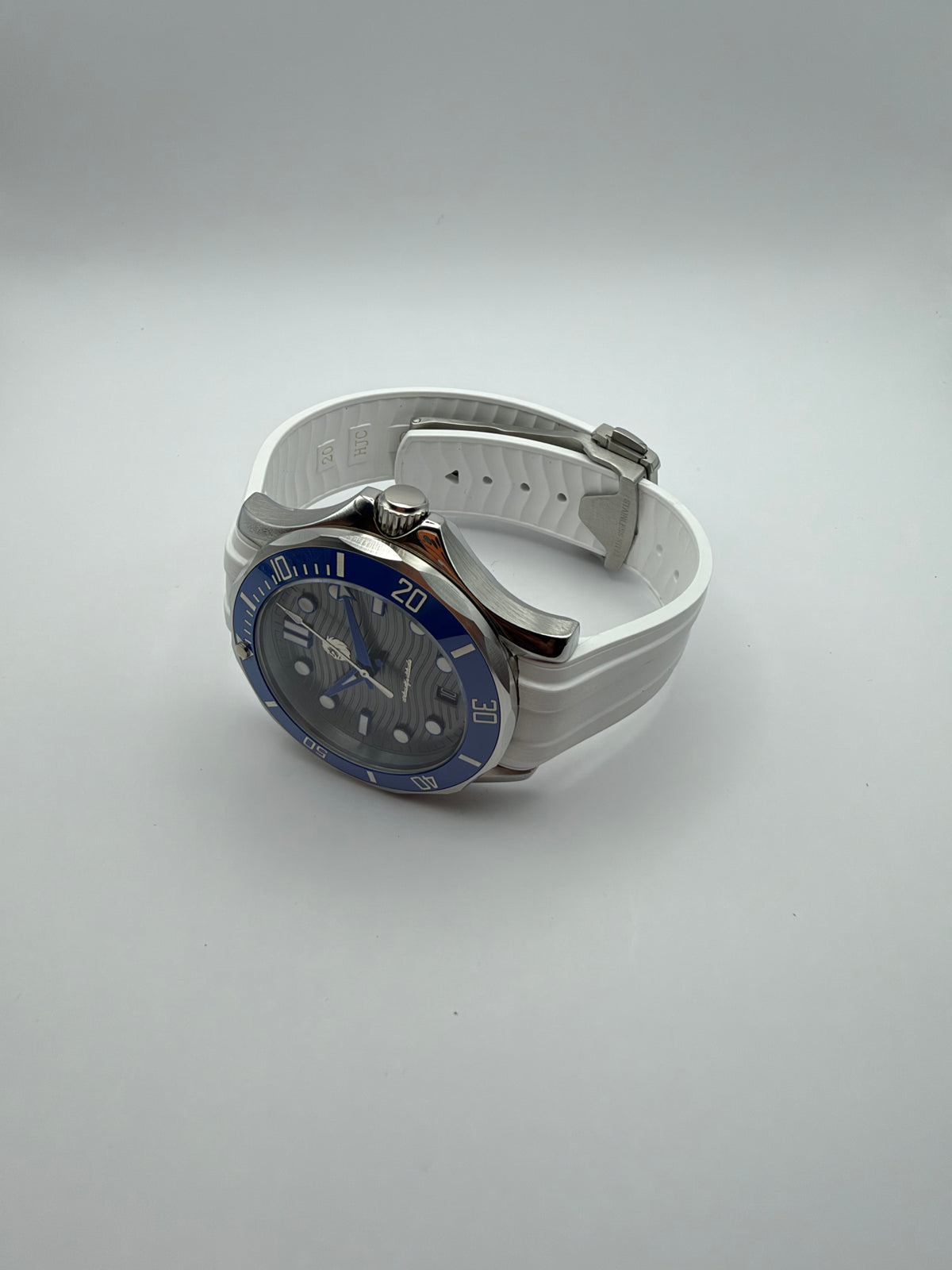 Thalassa Blue resting at an angle, showing the case profile and ridged white strap.
