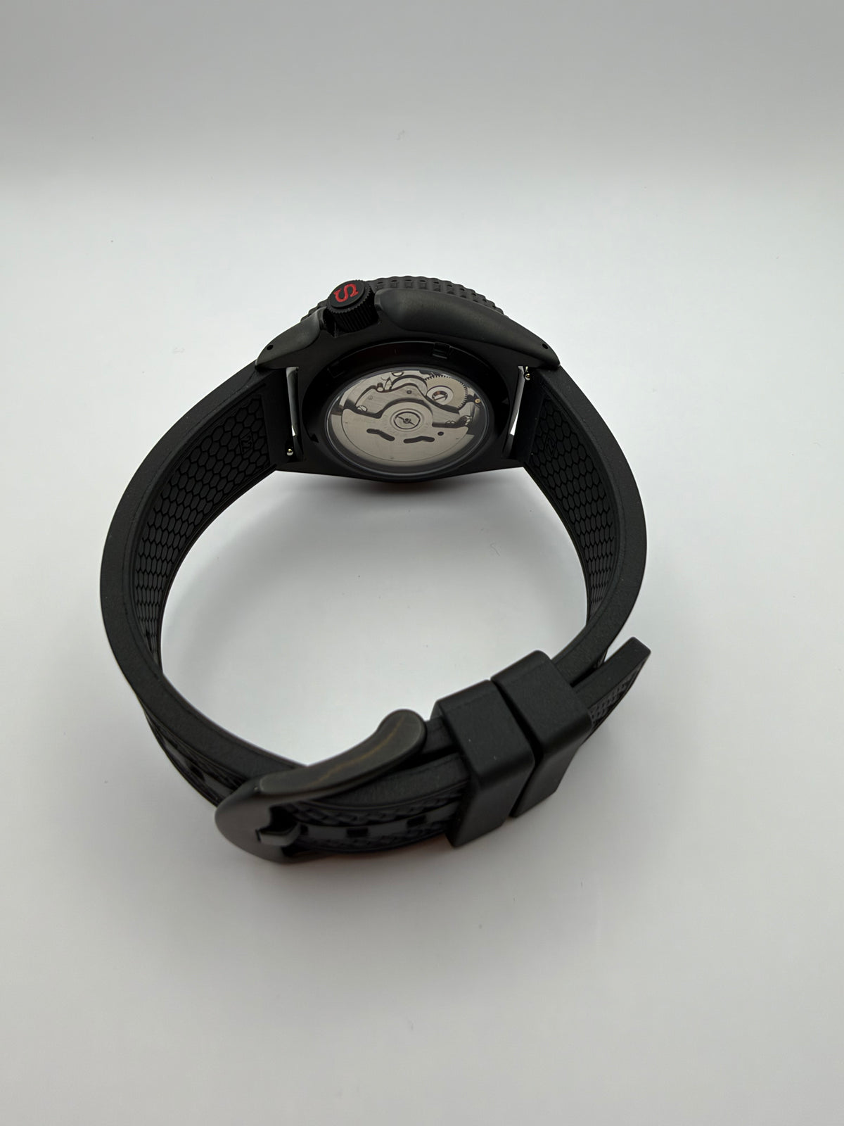 Rear view of the multicolor-dial watch showing a display caseback, black strap and black buckle.
