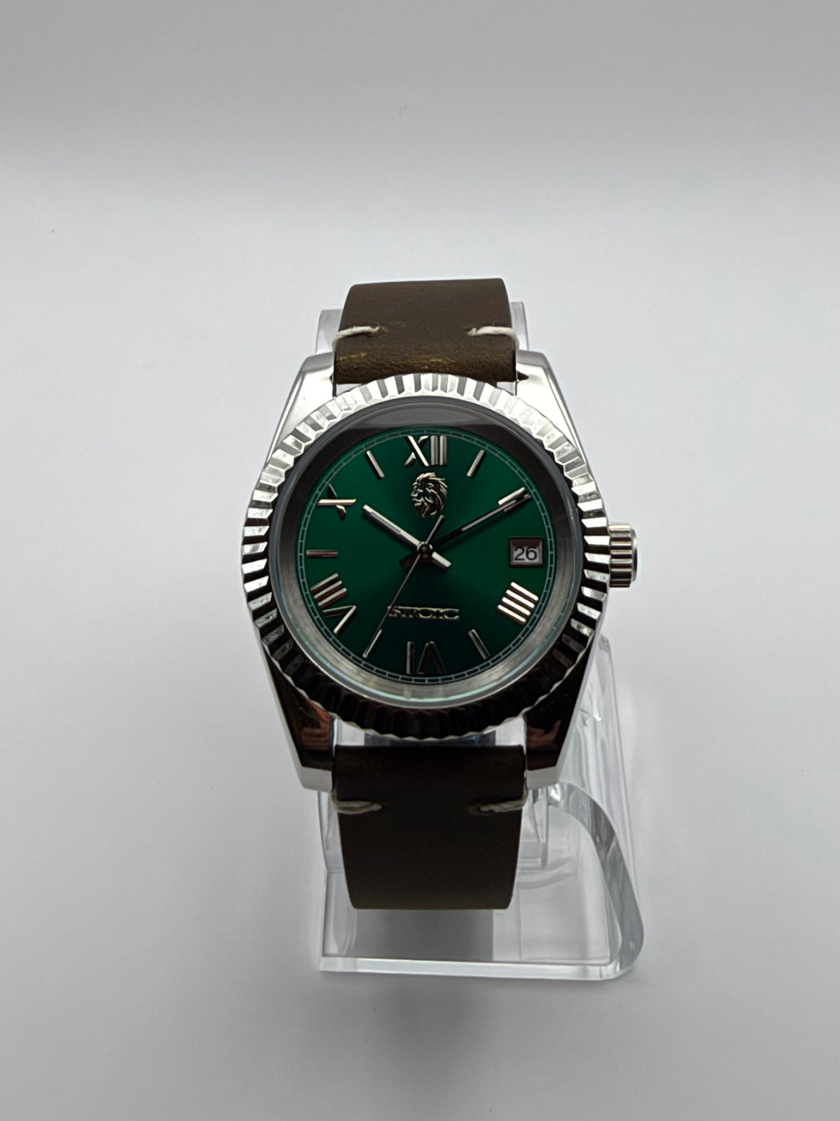 Verdant front view, with a green Roman-numeral dial, silver-tone fluted bezel and brown strap.