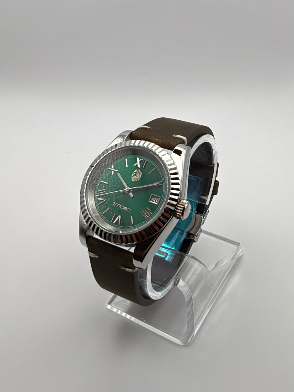 Verdant at an angle, showing the green dial, silver-tone case and brown stitched strap.